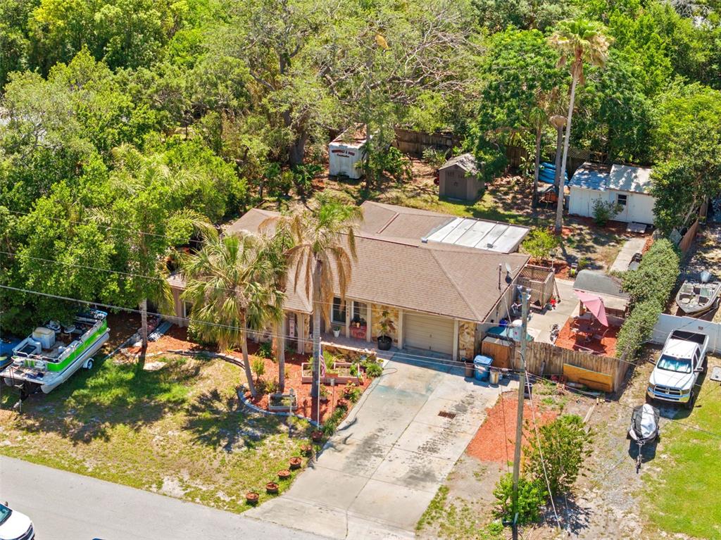 An aerial view of a single-story house with a driveway, palm trees, and backyard sheds — 7458 GATES CIRCLE, SPRING HILL, FL