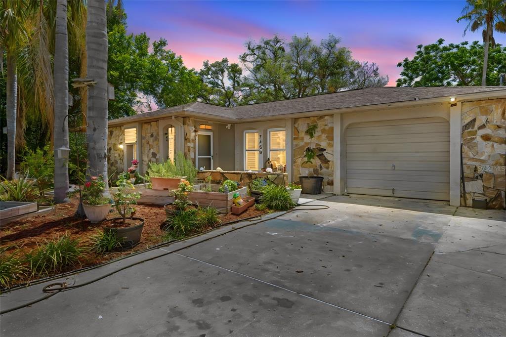 A single-story house with a stone facade, attached garage, and a front garden area — 7458 GATES CIRCLE, SPRING HILL, FL