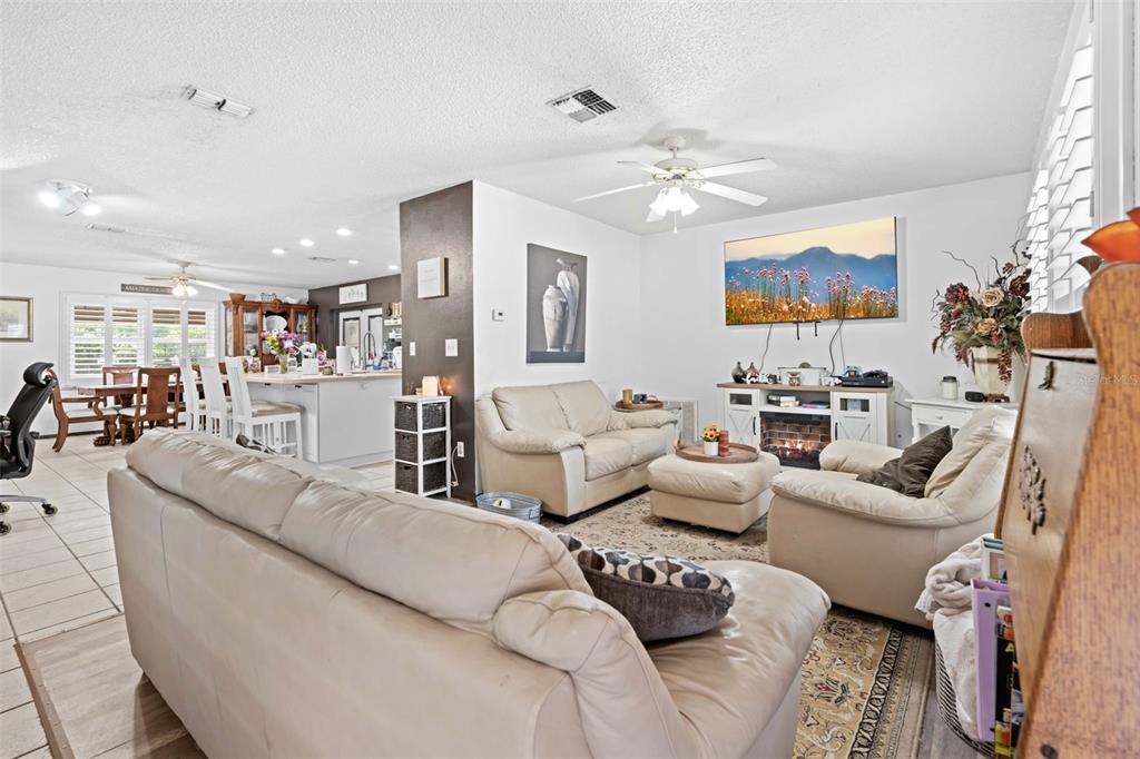 A living room with beige leather sofas, a fireplace, and an open-concept kitchen area — 7458 GATES CIRCLE, SPRING HILL, FL