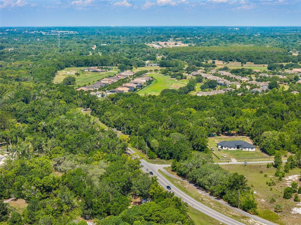 An aerial view shows a residential neighborhood, a golf course, and a road with trees — Lot 1 HOJIN STREET, SORRENTO, FL
