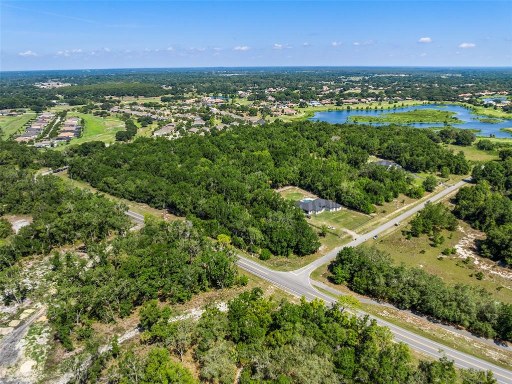 An aerial view shows a house with a pool surrounded by trees and nearby roads — Lot 1 HOJIN STREET, SORRENTO, FL