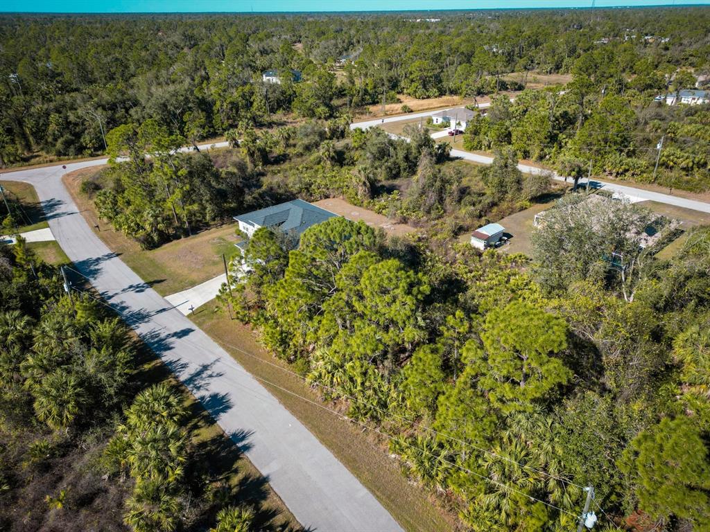 An aerial view shows a house with a dark roof surrounded by dense trees and roads — BELCHER AVENUE, NORTH PORT, FL