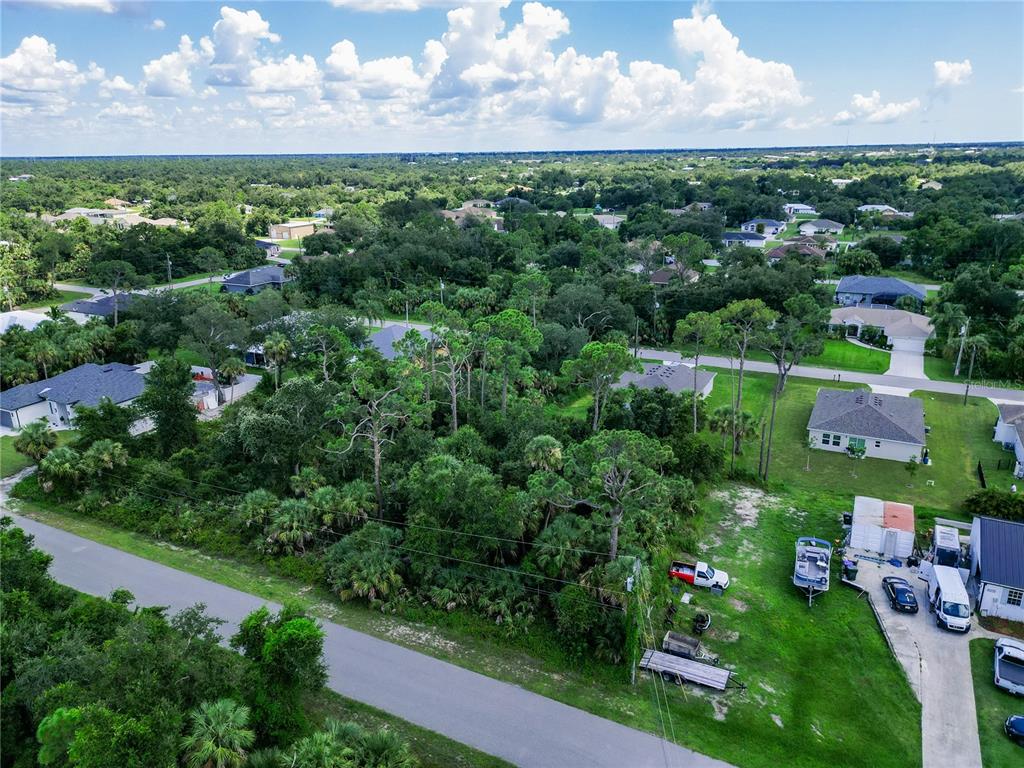 An aerial view shows a wooded residential lot situated between houses and a paved road — LEESBURG AVENUE, NORTH PORT, FL