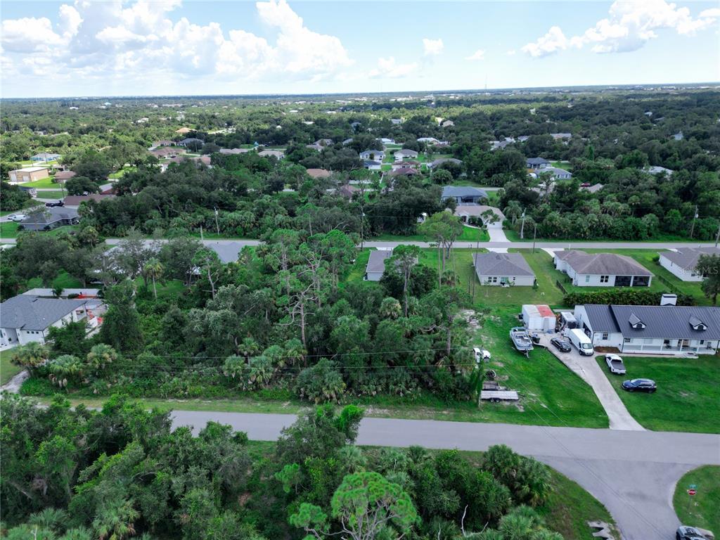 An aerial view shows a wooded residential lot situated between several houses and a paved road — LEESBURG AVENUE, NORTH PORT, FL