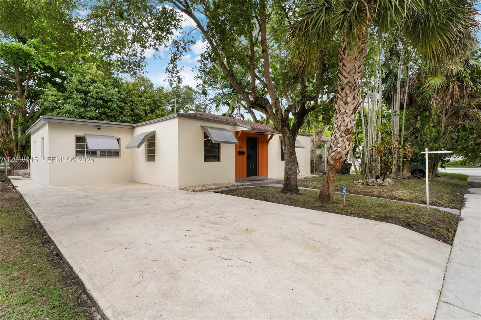 A single-story house with a concrete driveway, orange entryway, and mature trees in the yard — 6531 SW 57th Pl, South Miami FL 33143, SOUTH MIAMI, FL