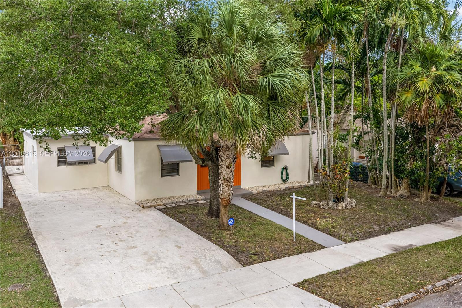 A single-story house with a concrete driveway, orange front door, and palm trees — 6531 SW 57th Pl, South Miami FL 33143, SOUTH MIAMI, FL