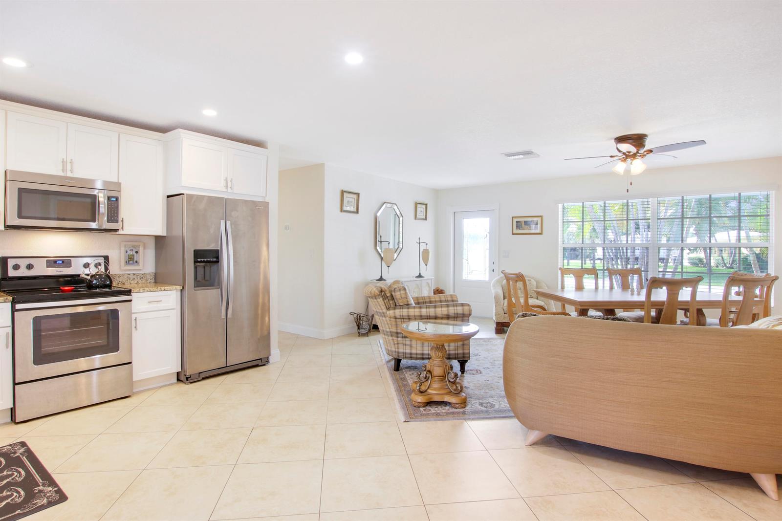 A kitchen with stainless steel appliances opens into a living and dining area — 19185 SE Homewood Avenue, Jupiter FL 33469, JUPITER, FL