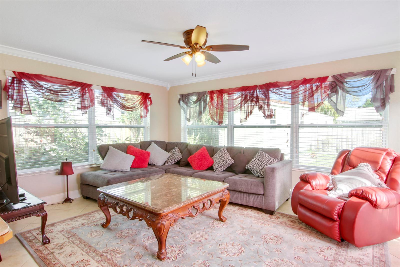A living room features a grey sectional sofa, a red recliner, and a marble coffee table — 19185 SE Homewood Avenue, Jupiter FL 33469, JUPITER, FL