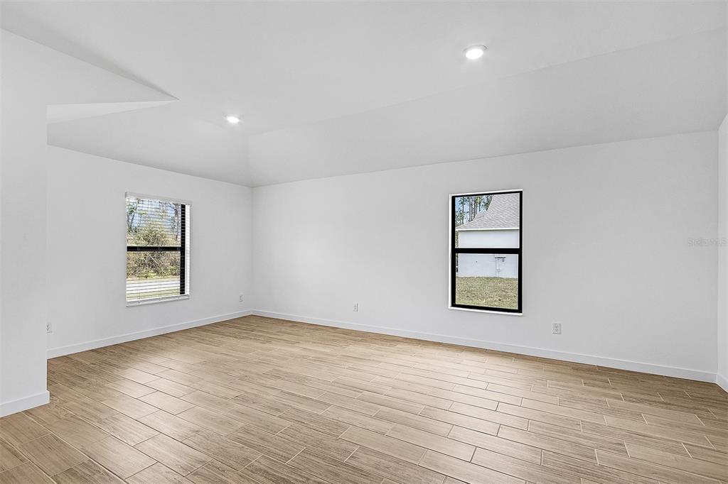 An empty room features white walls, recessed lighting, and light wood-look tile flooring — 4081 LONGWELL LANE, NORTH PORT, FL
