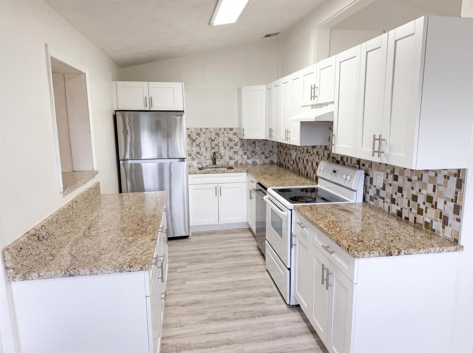 A kitchen features white cabinets, granite countertops, stainless steel appliances, and a mosaic tile backsplash — 752 Orchid Drive, Royal Palm Beach FL 33411, ROYAL PALM BEACH, FL
