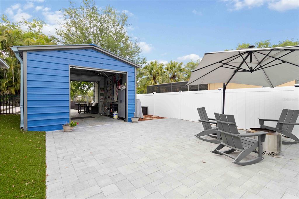 A backyard pool area features a tiki bar, stone patio, and palm trees — 807 IXORA AVENUE, ELLENTON, FL