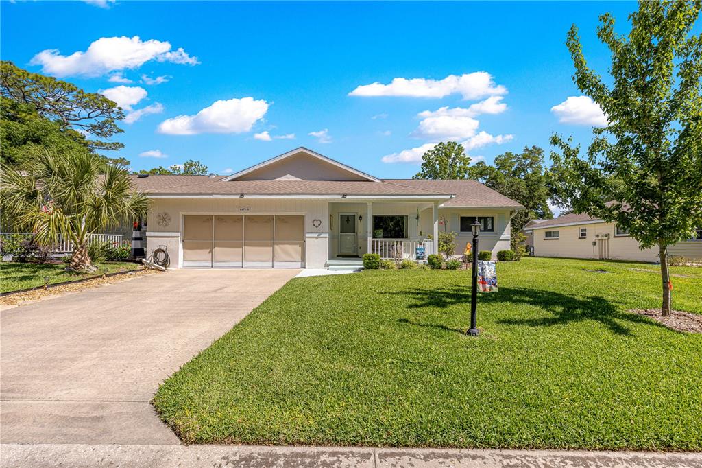 A single-story house with a two-car garage, a concrete driveway, and a front lawn — 8671 SW 97TH STREET UNIT G, OCALA, FL