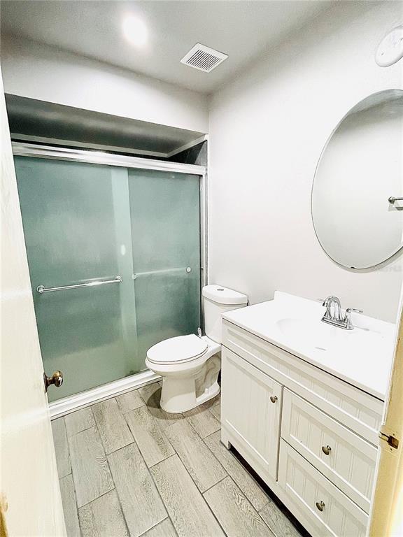 A bathroom features a white vanity, a toilet, and a glass-enclosed shower with tiled flooring — 1420 RIDGE LAKE COURT, LAKELAND, FL