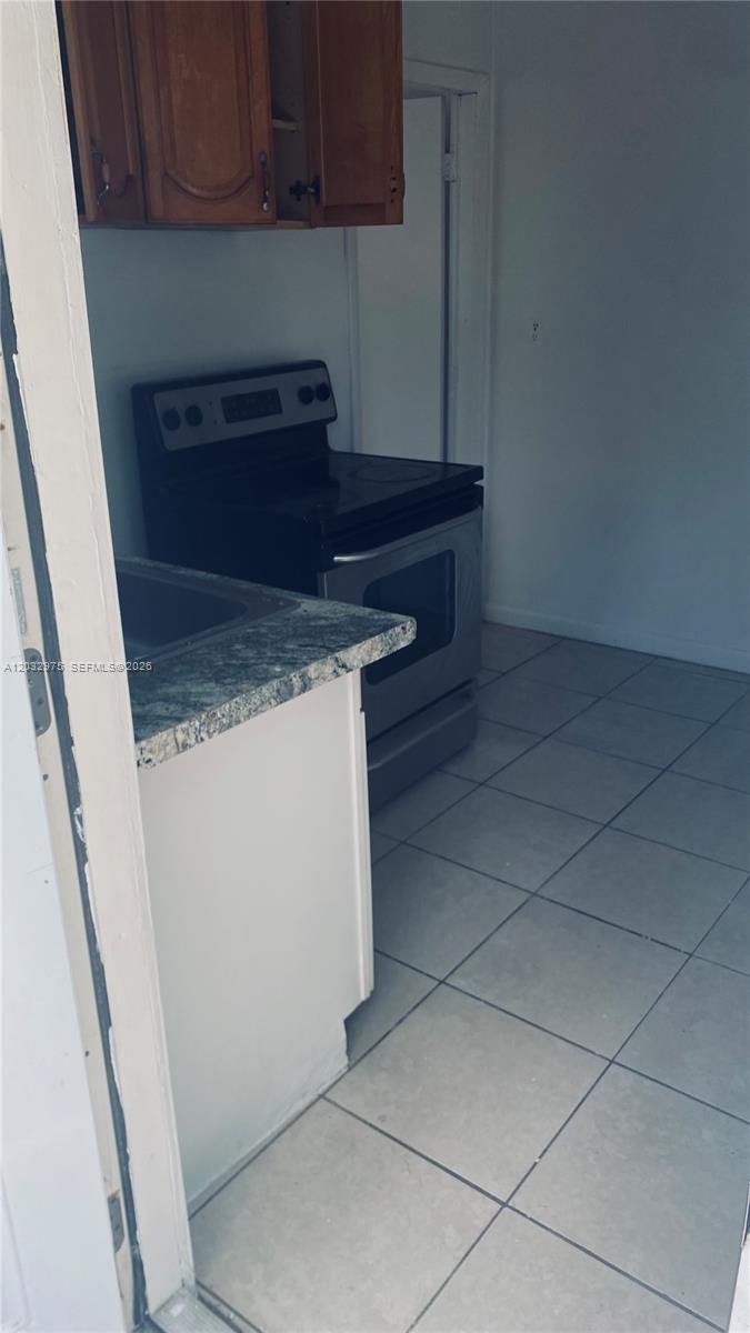 A kitchen features white tile flooring, a stainless steel stove, and a granite countertop — 1070 NW 147th St # 0, Miami FL 33168, MIAMI, FL