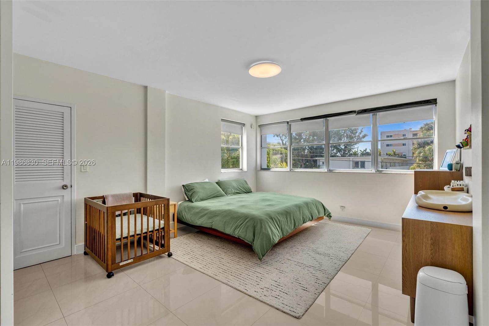 A bedroom features a low-profile bed, a wooden crib, and a changing table on tile — 9381 E Bay Harbor Dr # 202s, Bay Harbor Islands FL 33154, BAY HARBOR ISLANDS, FL