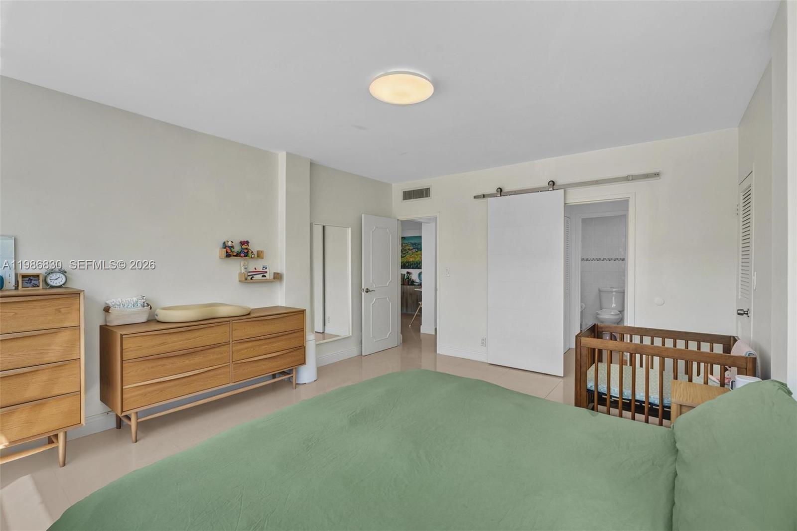 A bedroom features a green bed, wooden dressers, a crib, and a sliding barn door — 9381 E Bay Harbor Dr # 202s, Bay Harbor Islands FL 33154, BAY HARBOR ISLANDS, FL