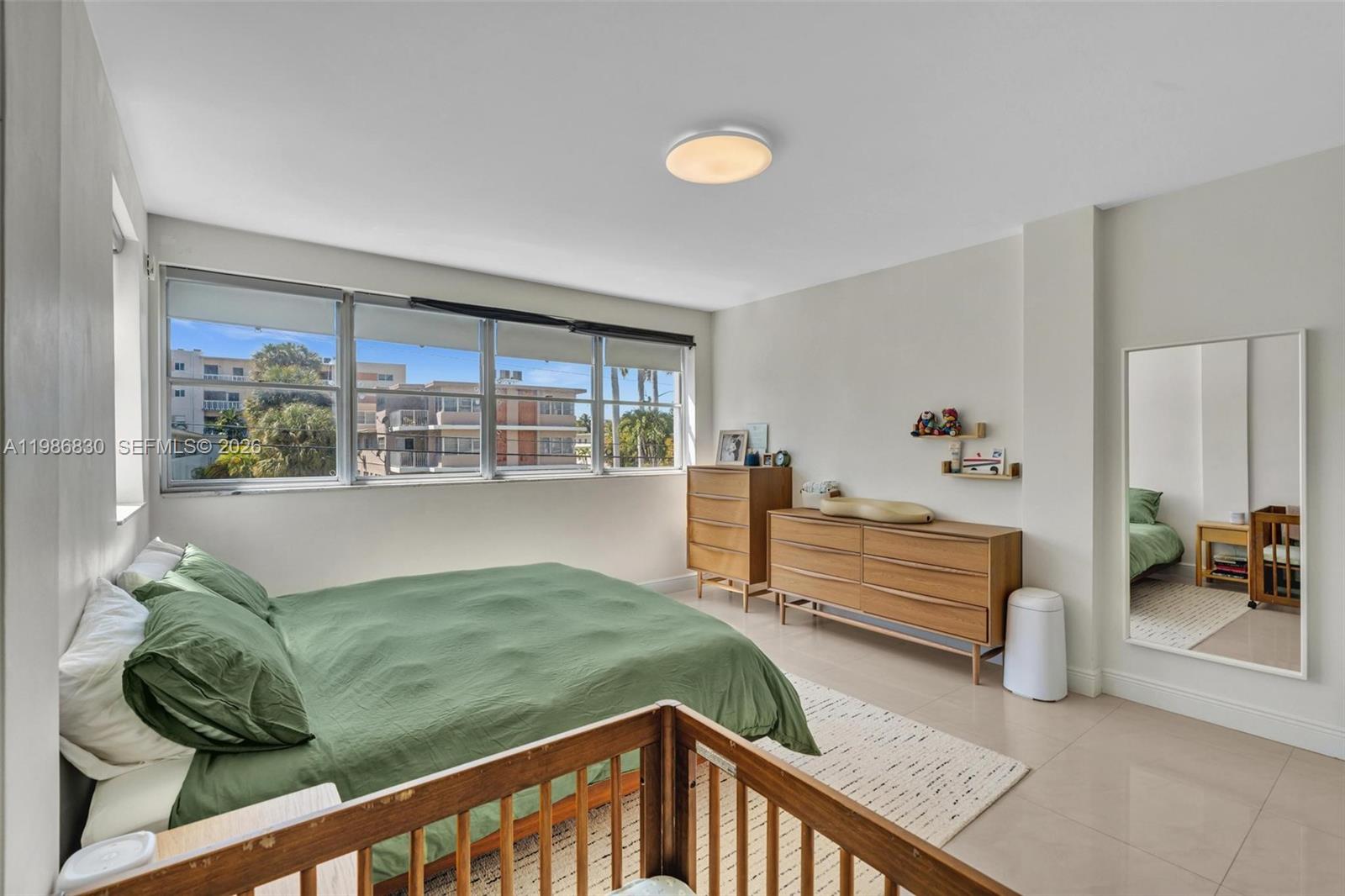A bedroom features a green bed, wooden furniture, a crib, and a large wall mirror — 9381 E Bay Harbor Dr # 202s, Bay Harbor Islands FL 33154, BAY HARBOR ISLANDS, FL