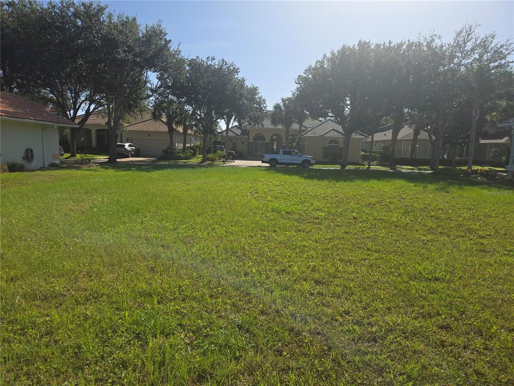 A vacant grassy lot sits in front of several suburban houses and trees — 86 FRONT STREET, PALM COAST, FL