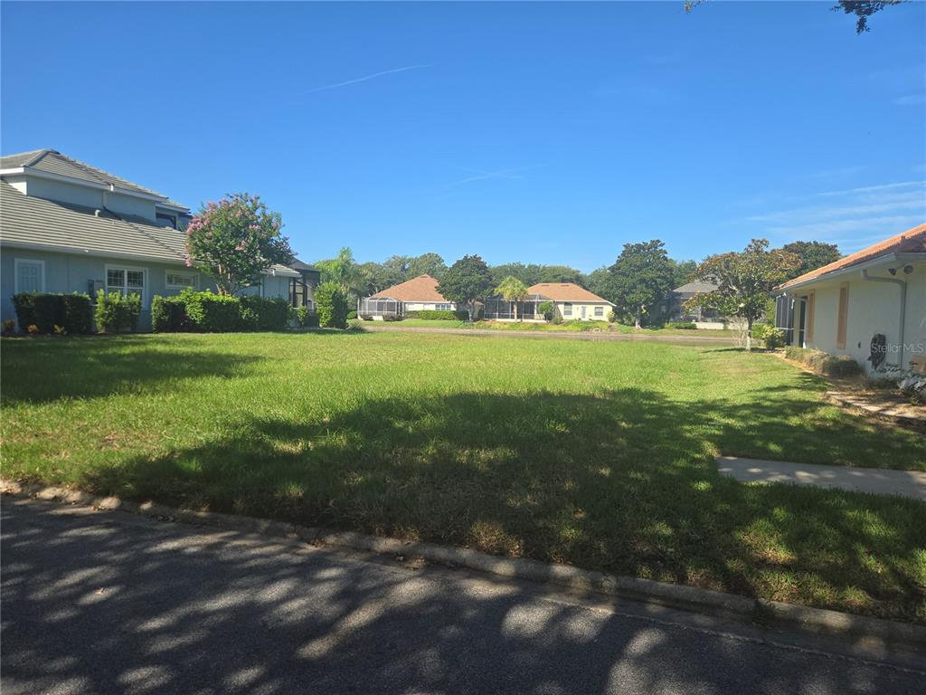 A vacant grassy lot sits between two suburban houses under a clear blue sky — 86 FRONT STREET, PALM COAST, FL