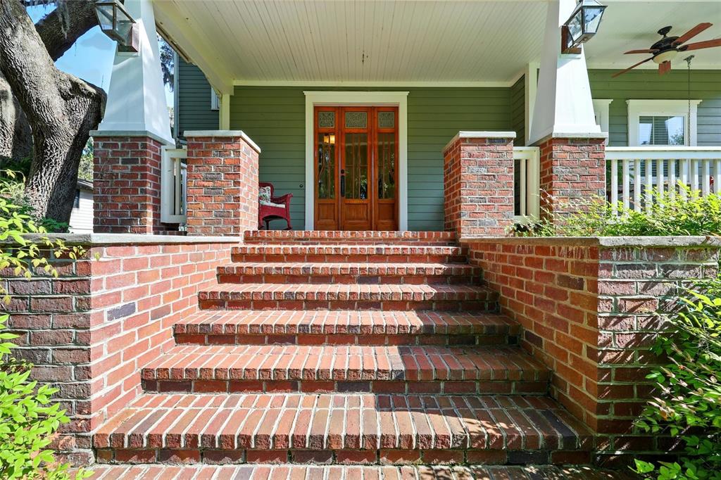 A brick staircase leads to a covered porch with a wooden front door and columns — 23014 NE 69TH AVENUE, MELROSE, FL