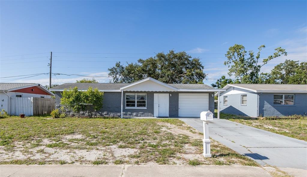 A single-story gray house with a white garage door and a white mailbox in front — 7734 COVENTRY DRIVE, PORT RICHEY, FL