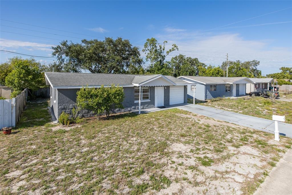 A single-story gray house with a concrete driveway and a sparse, grassy front yard — 7734 COVENTRY DRIVE, PORT RICHEY, FL