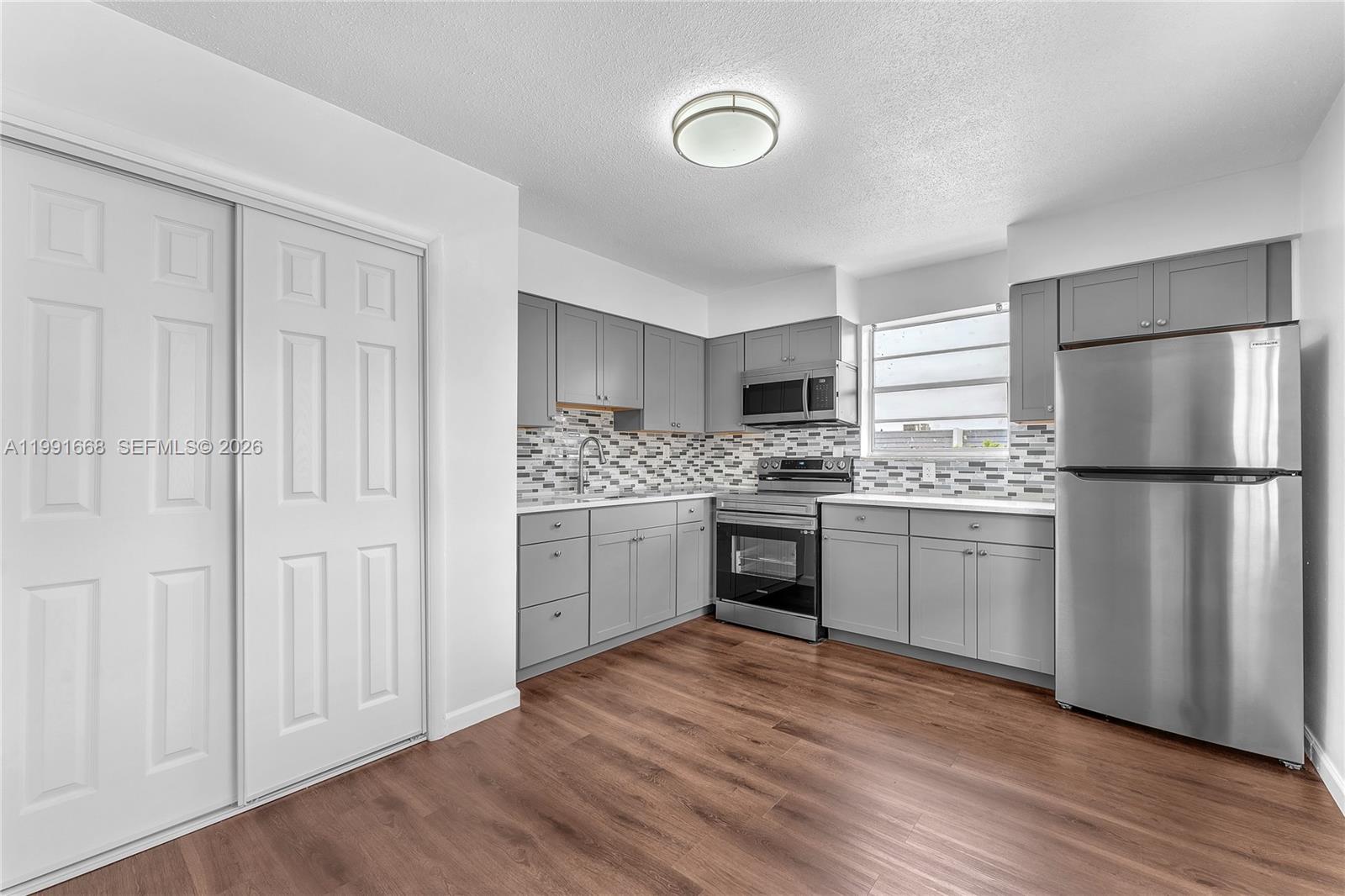 A kitchen features gray cabinets, stainless steel appliances, a tiled backsplash, and wood-look flooring — 3750 SW 59th Ave # 3, Davie FL 33314, DAVIE, FL