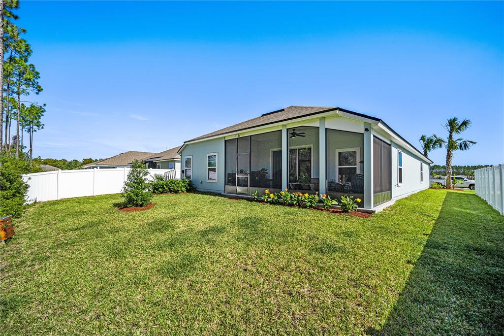 The exterior of a light blue house features a screened-in lanai and a fenced backyard — 14 LUMBER JACK TRAIL, PALM COAST, FL