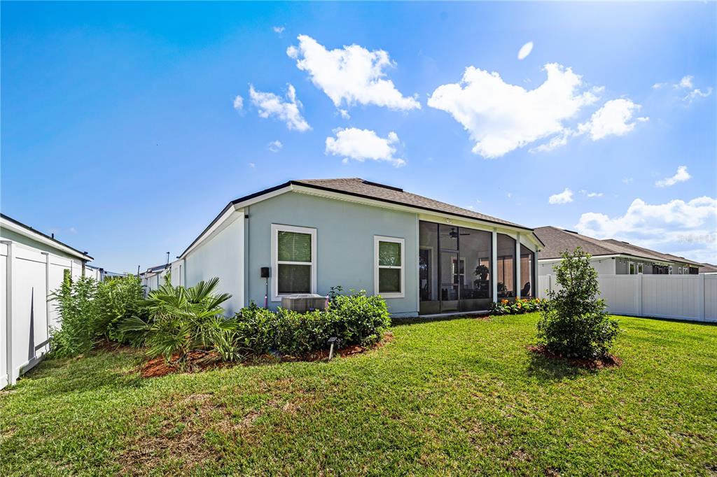 The exterior of a light blue house features a screened-in porch and a grassy backyard — 14 LUMBER JACK TRAIL, PALM COAST, FL