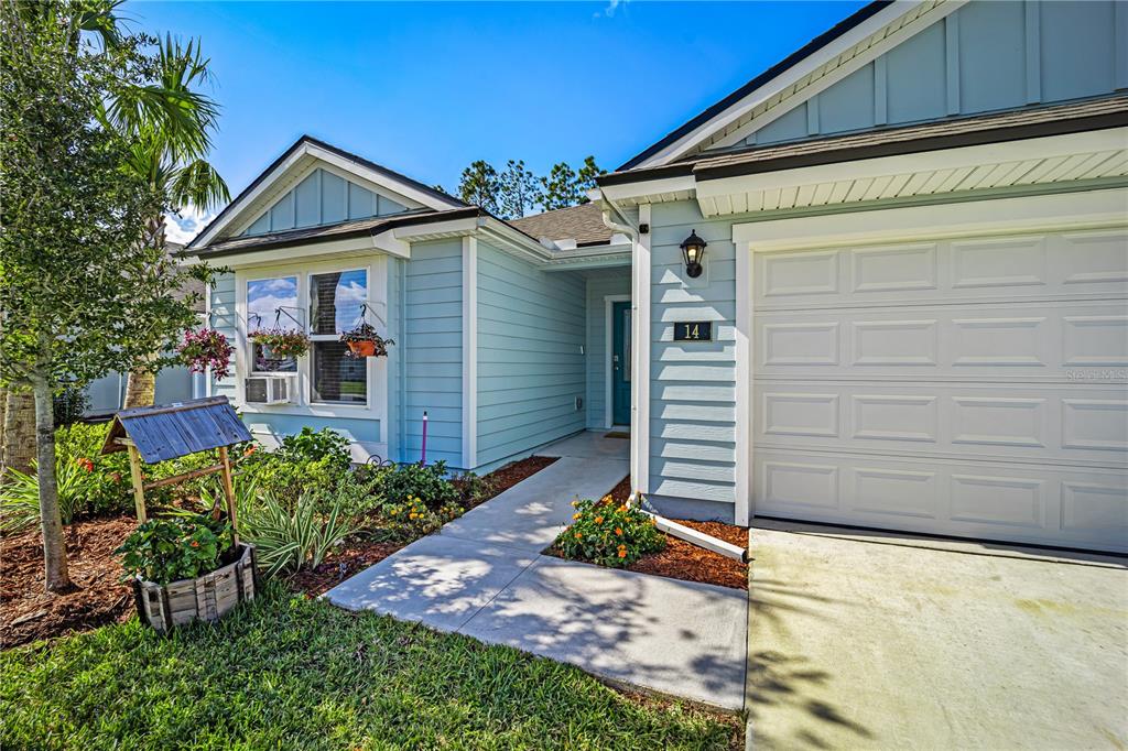 A light blue house with a white garage door, a front walkway, and a wishing well — 14 LUMBER JACK TRAIL, PALM COAST, FL