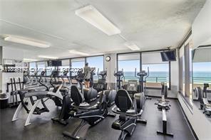 A gym with multiple exercise machines and large windows overlooking the ocean — 5555 Collins Ave # 14U, Miami Beach FL 33140, MIAMI BEACH, FL