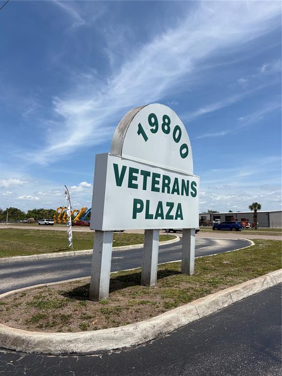 A sign for Veterans Plaza stands on a concrete island in a parking lot — 19800 VETERANS BOULEVARD UNIT D7, PORT CHARLOTTE, FL