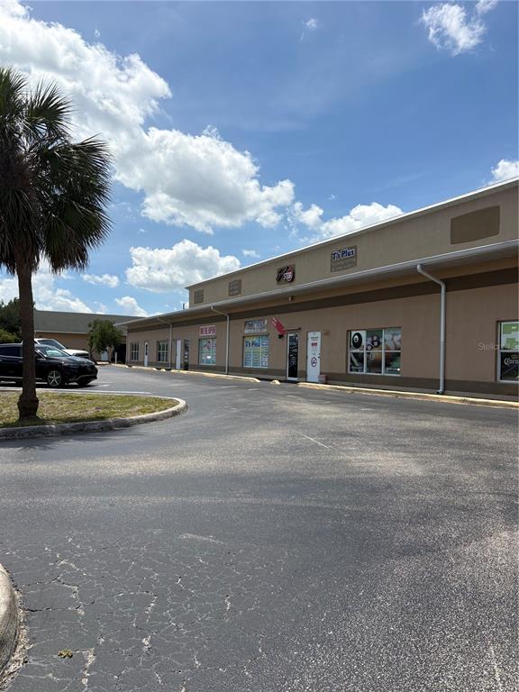 A low-rise commercial building with a parking lot and a palm tree in the foreground — 19800 VETERANS BOULEVARD UNIT D7, PORT CHARLOTTE, FL
