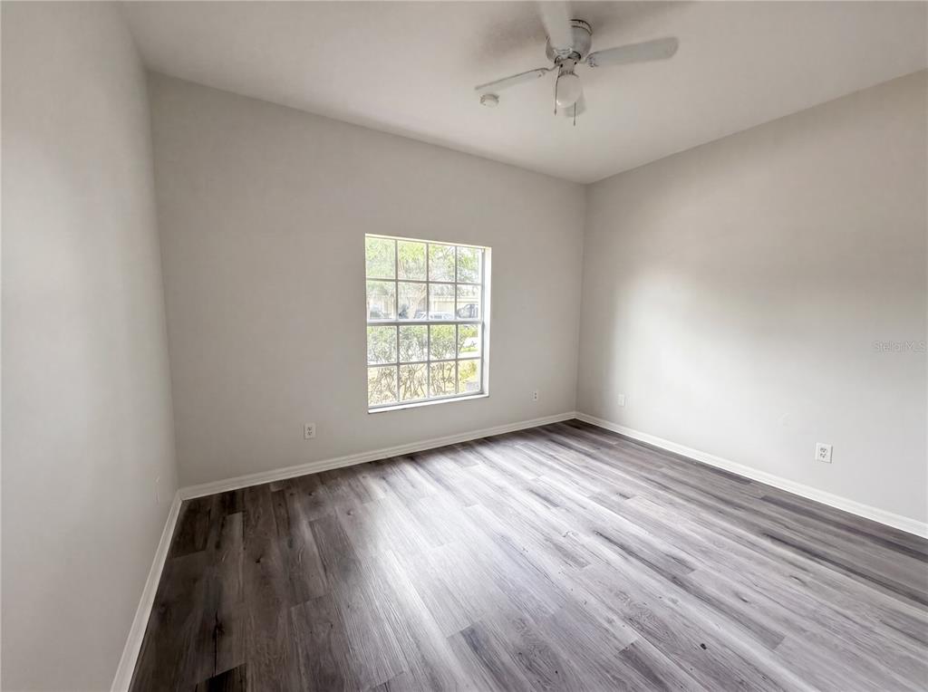 An empty bedroom features light gray walls, a ceiling fan, and wood-look laminate flooring — 3408 GROVE BLOSSOM LANE, PLANT CITY, FL