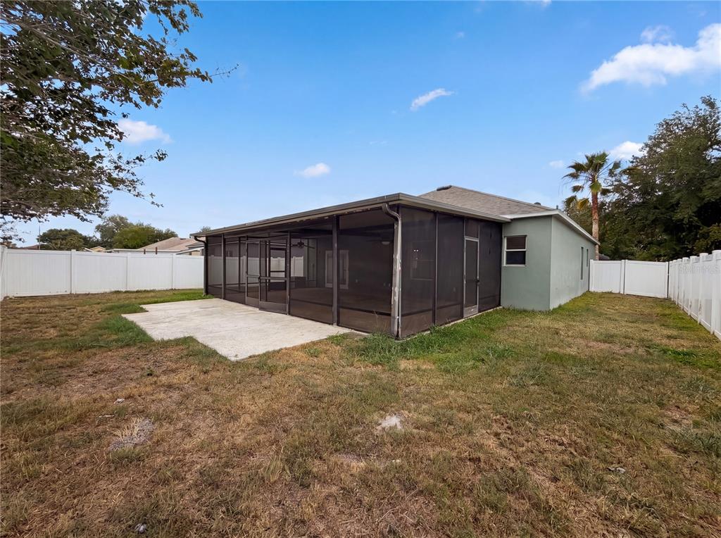 A backyard view shows a house with a screened-in patio and a concrete slab — 3408 GROVE BLOSSOM LANE, PLANT CITY, FL