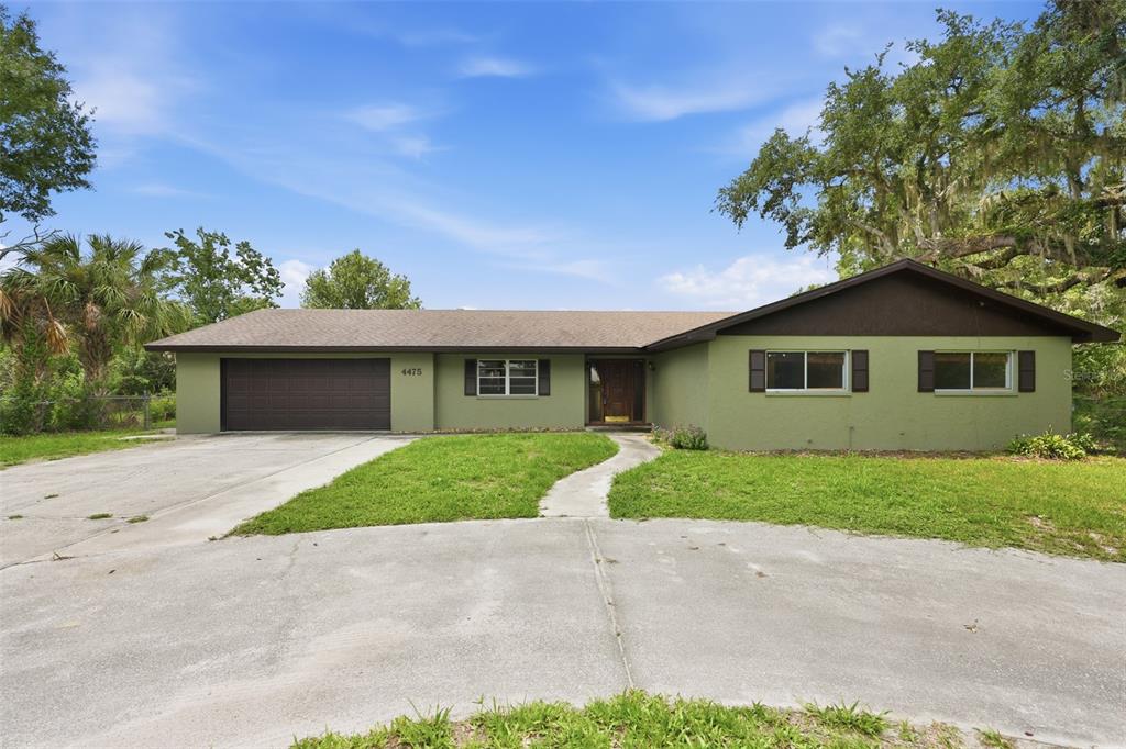 A single-story house with a green exterior, a brown roof, and an attached garage — 4475 CYPRESS COUNTRY LANE, LAKELAND, FL
