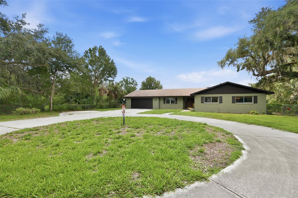A single-story house with a green exterior, brown roof, and a curved concrete driveway — 4475 CYPRESS COUNTRY LANE, LAKELAND, FL