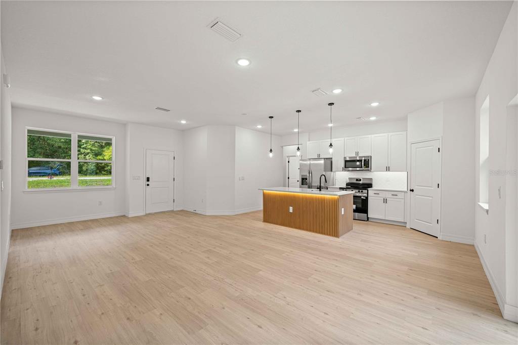 An open-concept kitchen and living area features light wood flooring, white cabinetry, and a slatted island — 1197 W G MARTINELLI BOULEVARD, CITRUS SPRINGS, FL