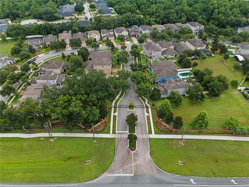 An aerial view shows the gated entrance to a suburban residential neighborhood with houses — 2651 PEONY DRIVE, OVIEDO, FL