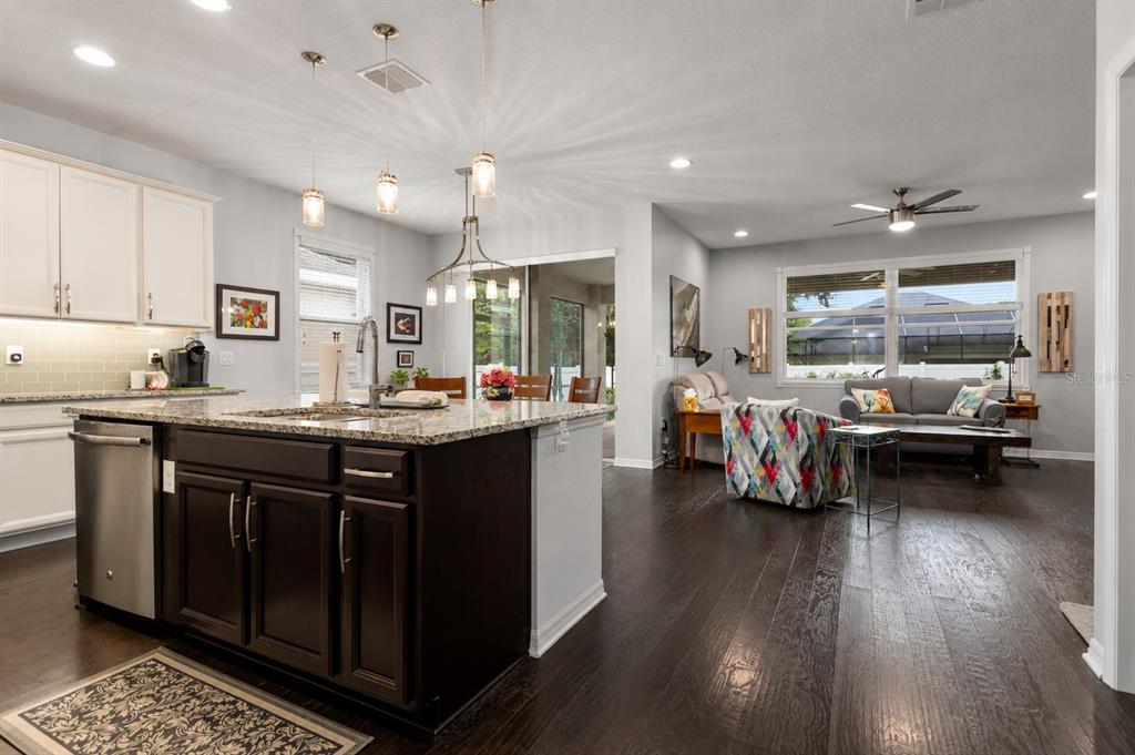 An open-concept kitchen with a dark island and granite countertops overlooks a living room area — 2651 PEONY DRIVE, OVIEDO, FL