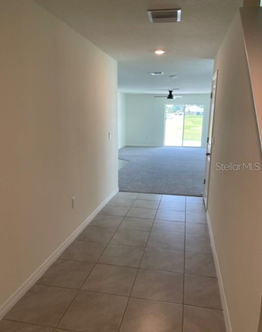 An open-concept kitchen with white cabinets and an island overlooks a carpeted living area — 6484 SE 4TH LANE, OCALA, FL