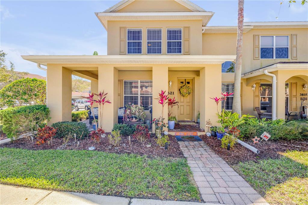 A two-story tan stucco townhouse features a covered front porch and a paved walkway — 3621 CASELLO DRIVE, NEW SMYRNA BEACH, FL