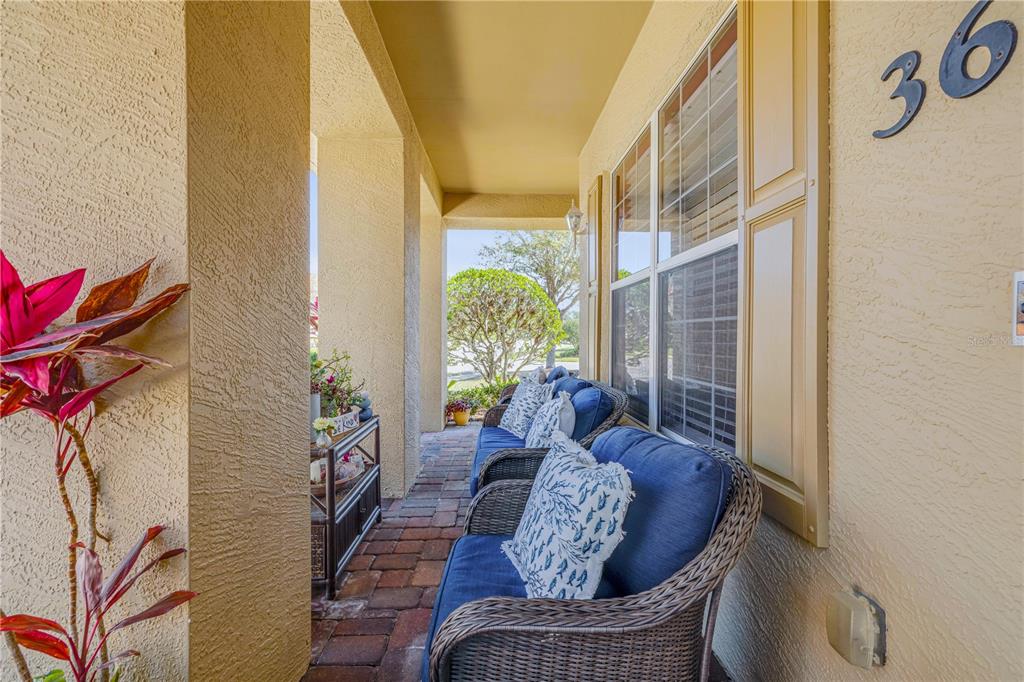 A covered porch features brick flooring, wicker furniture with blue cushions, and a house number — 3621 CASELLO DRIVE, NEW SMYRNA BEACH, FL