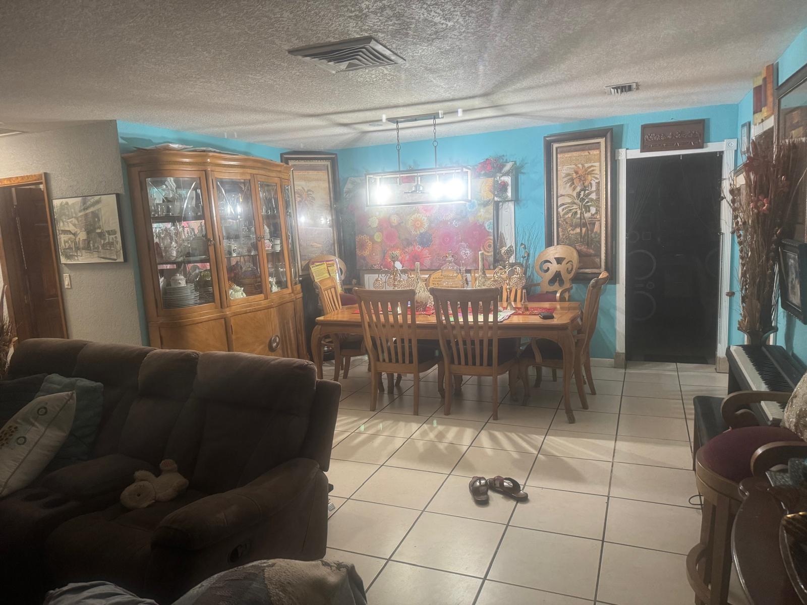 A dining area with a wooden table, chairs, and hutch against bright blue walls — 6218 NW 17th Street, Margate FL 33063, MARGATE, FL