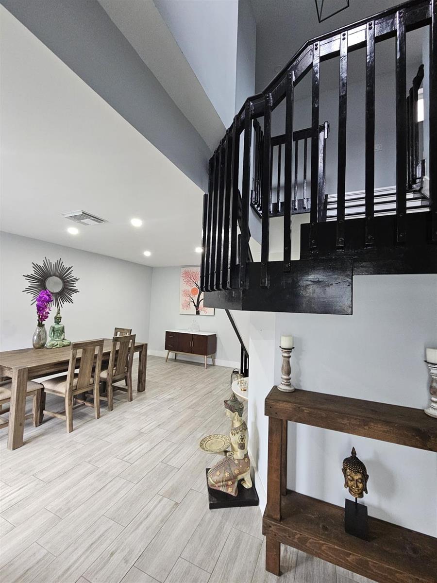 A dining area with a wooden table and chairs sits beneath a black staircase — 16218 SW 100th Terrace # 16218, Miami FL 33196, MIAMI, FL