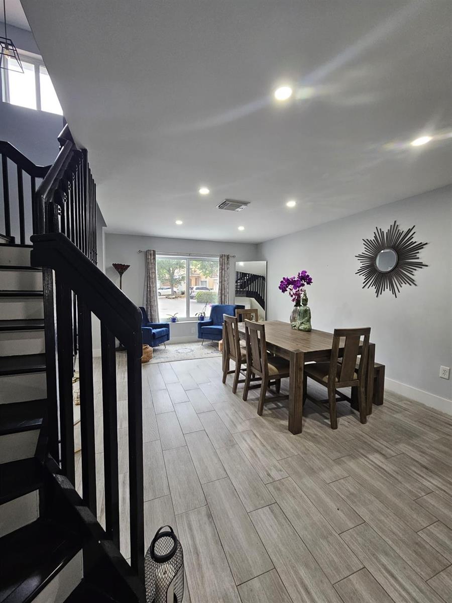 A dining room features a wooden table, chairs, a sunburst mirror, and a staircase — 16218 SW 100th Terrace # 16218, Miami FL 33196, MIAMI, FL
