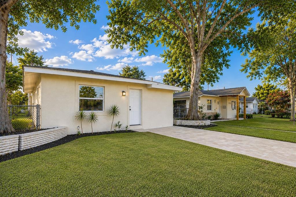 A light-colored single-story house with a paved driveway and mature trees in the front yard — 5532 6TH AVENUE N, ST PETERSBURG, FL