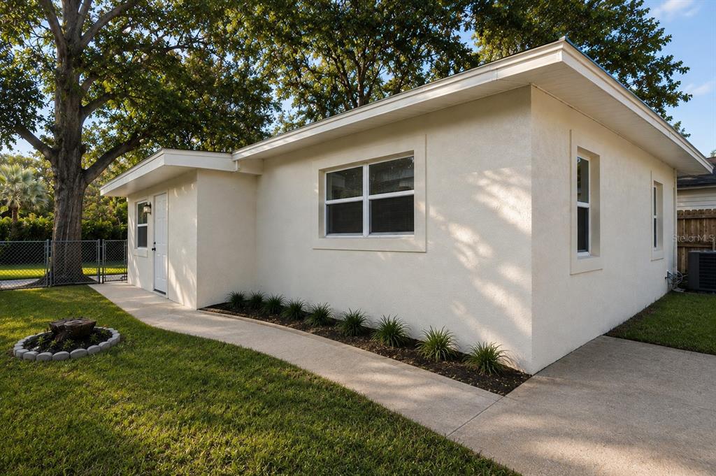 A single-story house with white stucco walls, a concrete walkway, and a small landscaped garden — 5532 6TH AVENUE N, ST PETERSBURG, FL