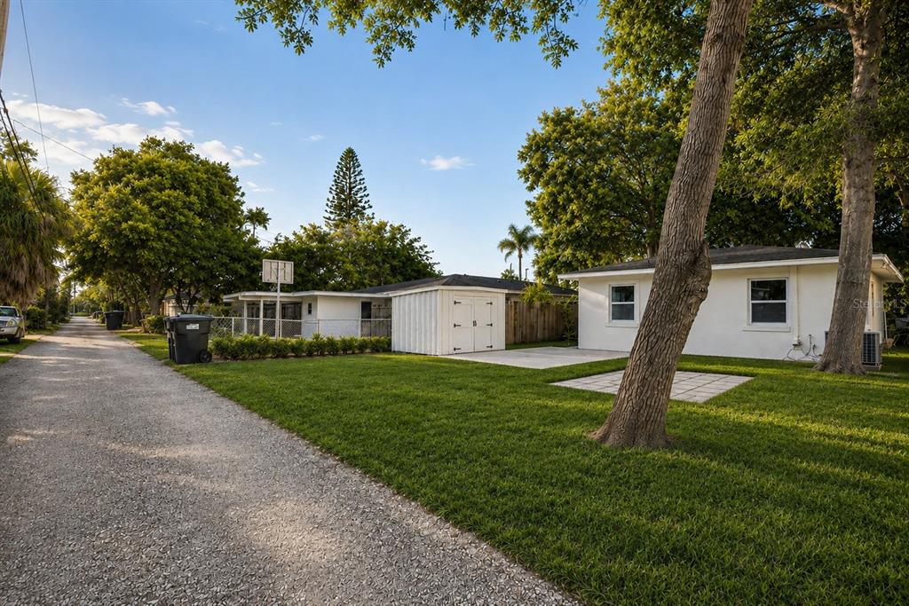 A gravel alley runs alongside a white house with a shed and a grassy yard — 5532 6TH AVENUE N, ST PETERSBURG, FL
