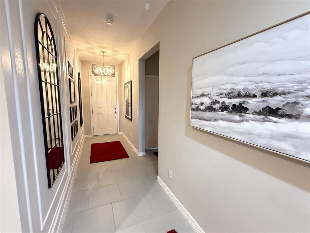 A bright entryway features light tile flooring, a white front door, and decorative wall art — 123 GREEN BRANCH BOULEVARD, GROVELAND, FL